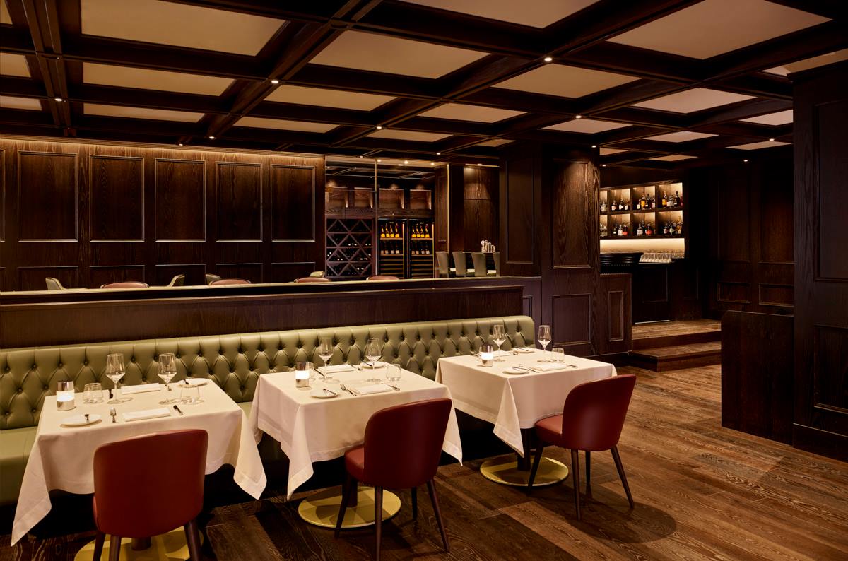 Tufted banquette seating above wide-plank parquet flooring