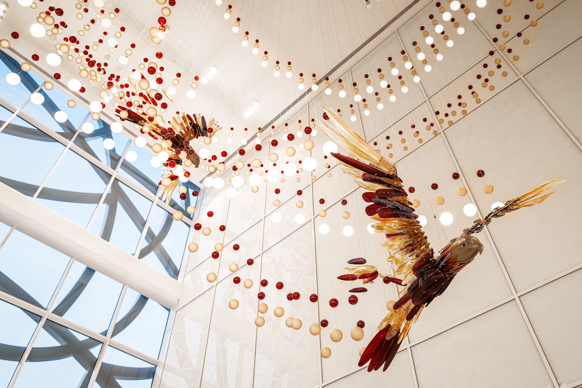 Suspended glass bird sculpture in flight above the concourse atrium