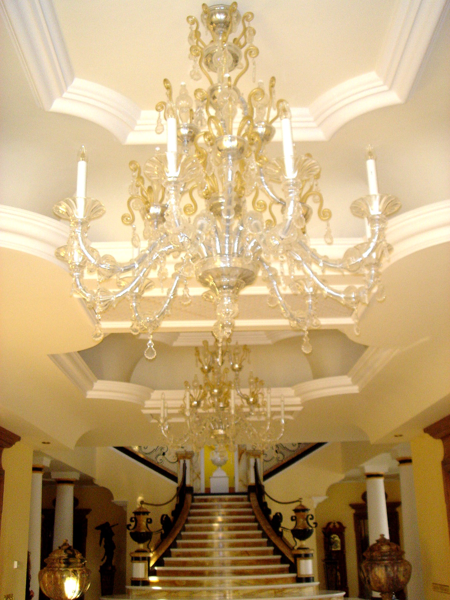 Double-height entrance hall with tiered Murano glass chandeliers above a marble stair